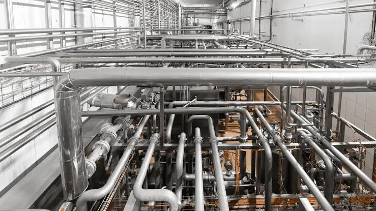 An overhead view of stainless process and supply piping in an industrial mechanical space — plumbing contractor insurance in Rhode Island