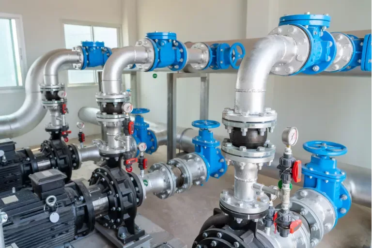 Stainless supply headers, gate valves, and booster pumps inside a commercial pump room — plumbing contractor insurance in Minnesota